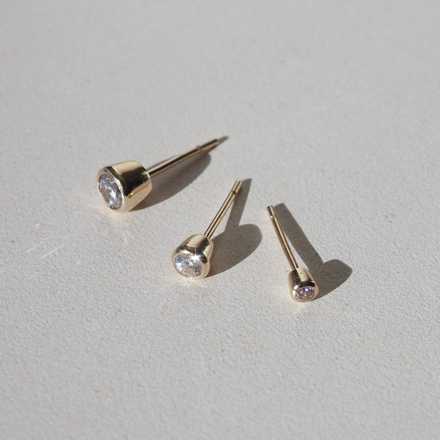 0.20 TCW Round Cut Moissanite Bezel Earrings in Gold 1